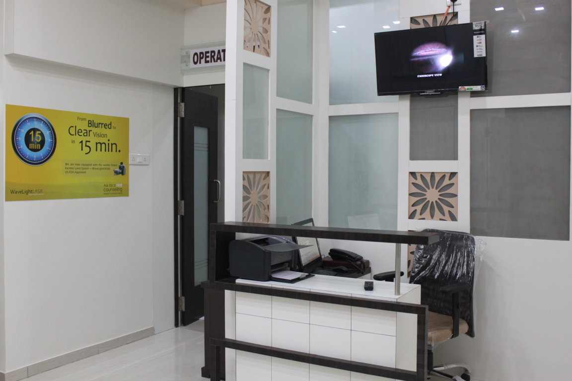 Theatre-side reception at Insight Institute with a live endoscope-view monitor on the feature wall and the operation theatre door at left